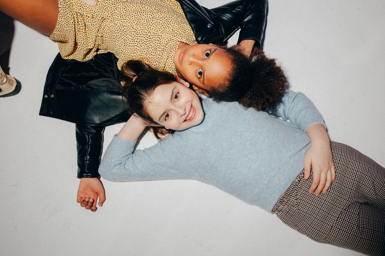 Two cheerful children lying down, showcasing friendship and diversity with genuine smiles.