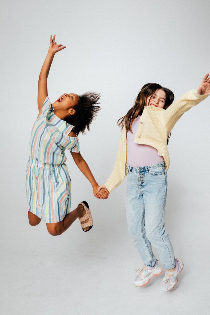Two girls joyfully jumping, expressing fun and happiness in a studio setting.